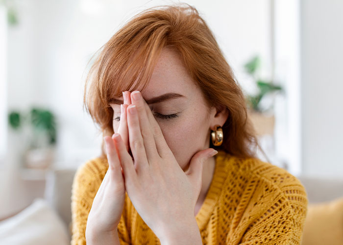 Woman in yellow sweater, appearing stressed, with hands covering her face; capturing a wild audition story moment.
