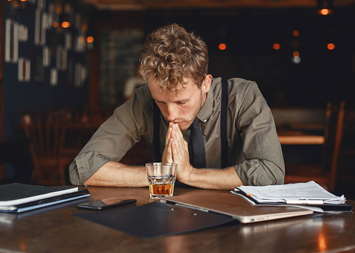 College student preparing for midterm, sitting at a table with a drink, deep in thought.