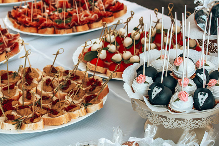 Wedding menu with assorted appetizers, featuring bruschetta and cake pops decorated as a bride and groom.