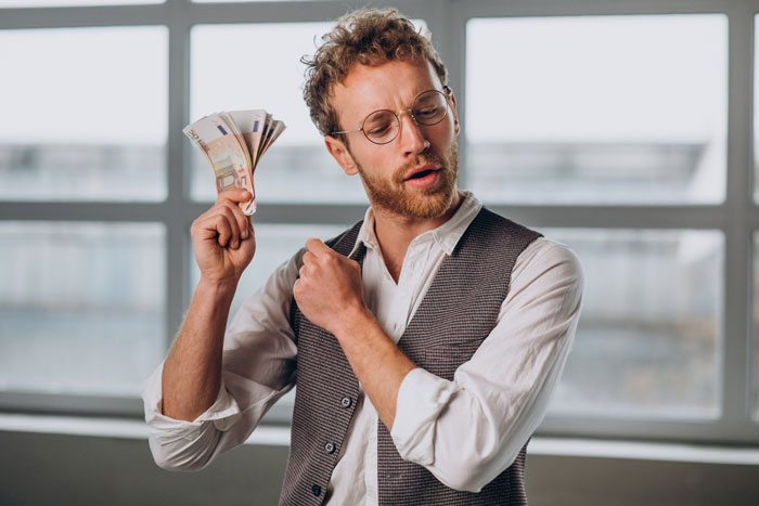 Man holding cash with an entitled expression, wearing glasses and a vest, symbolizing cruise jackpot expectation. Man holding cash with an entitled expression, wearing glasses and a vest, symbolizing cruise jackpot expectation.