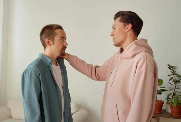Two men in casual clothes having a serious conversation in a living room setting. Two men in casual clothes having a serious conversation in a living room setting.