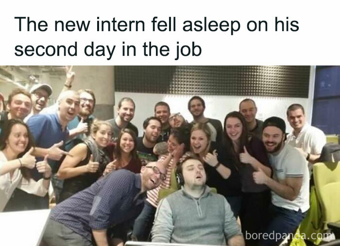 Group smiling around a sleeping intern at work, capturing a funny meme moment to distract from burnout.