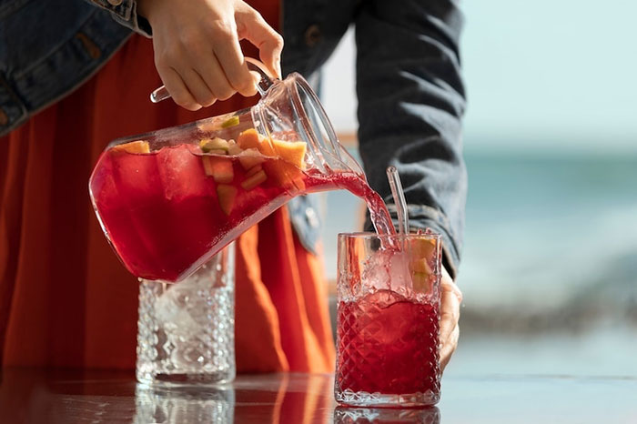Woman pouring fruit punch into a glass at a work party.