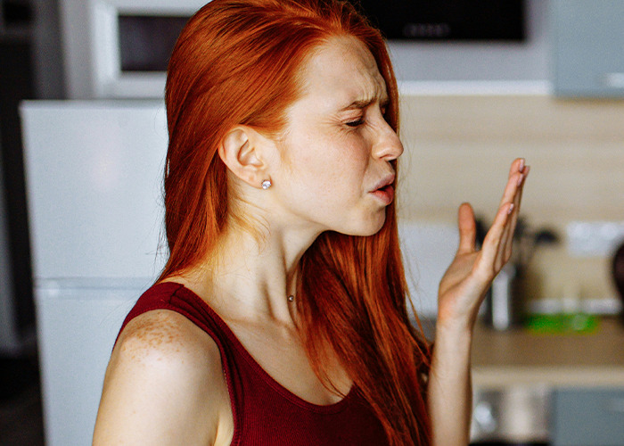 Woman looking displeased, symbolizing frustration over failed diet experiences in a kitchen setting.