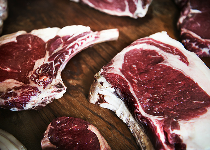Raw steaks on a wooden board, possibly referencing worst diets with excessive meat consumption.