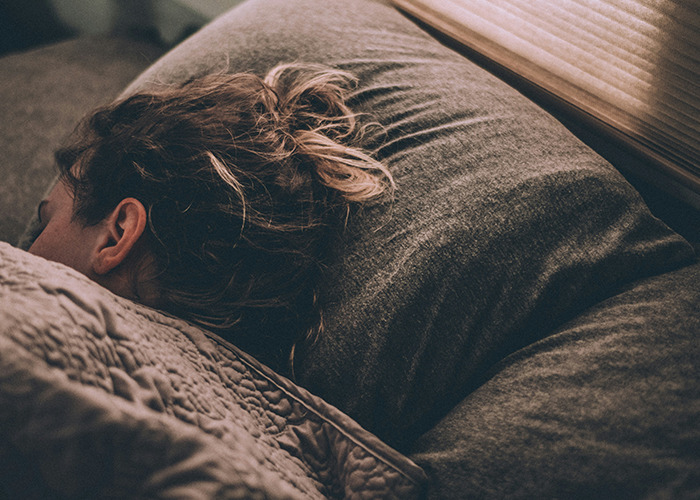Person sleeping on a bed under a gray blanket, representing the exhaustion from the worst diets.
