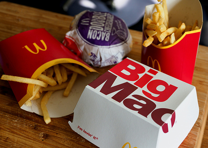 Fast food meal on a table, including fries, a burger, and a Big Mac box, illustrating unhealthy diet choices.