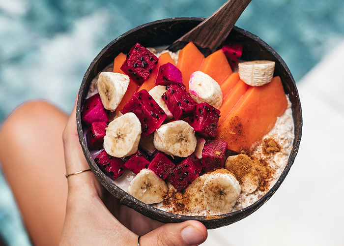 A colorful fruit bowl with banana, dragon fruit, and papaya, illustrating diet choices in a tropical setting.