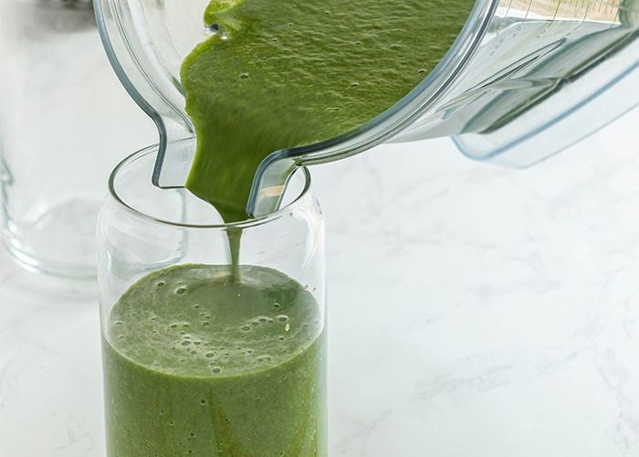 Green smoothie being poured from a blender into a glass, related to worst diets theme.