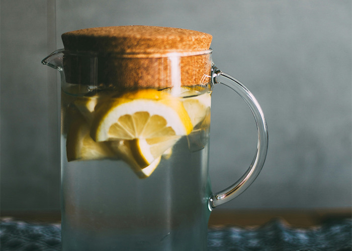 Glass pitcher with lemon slices, representing diet themes, against a light backdrop.