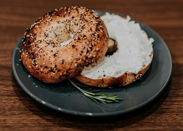 Bagel with cream cheese on a plate, representing worst diets shared by people.