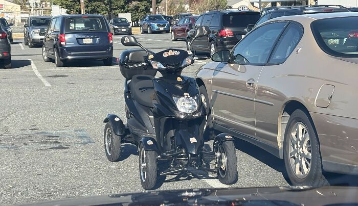Mobility scooter parked between cars, causing a parking inconvenience.