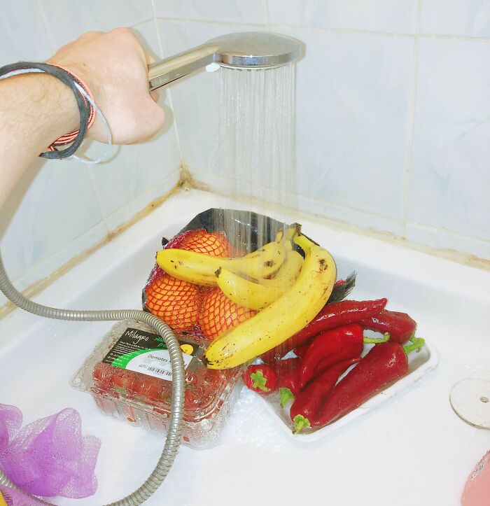 Hand holding a showerhead over fruits in a shower for a fun April Fools’ prank.