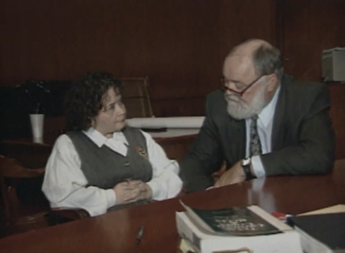 Two individuals seated at a table, discussing the pop star Selena assassination case.