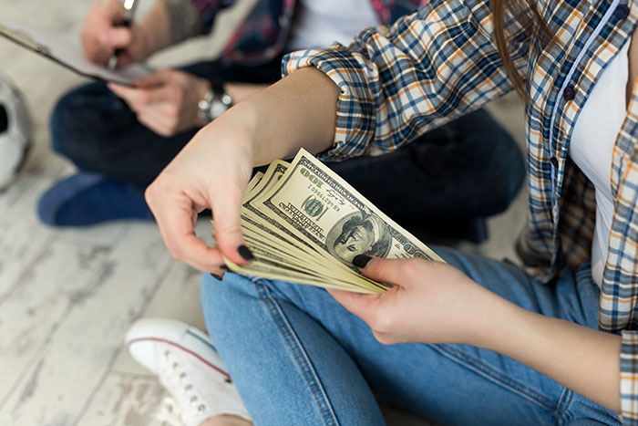 Woman counting money, represents charging son rent due to high earnings.