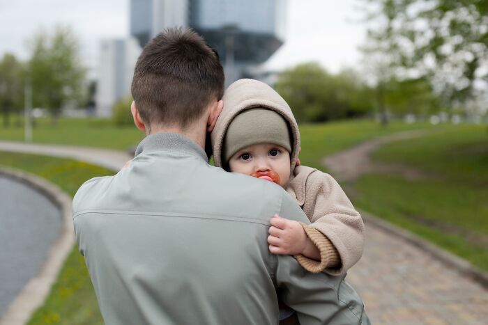 Father carrying a baby in a park, showcasing things that get more hate than they deserve.