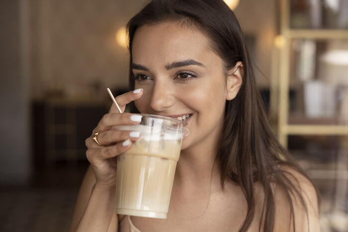 Woman enjoying iced coffee, symbolizing things that get more hate than deserved.
