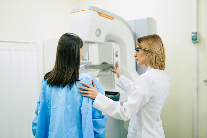 A technician assists a woman in a medical exam room, highlighting modern inventions in healthcare technology.