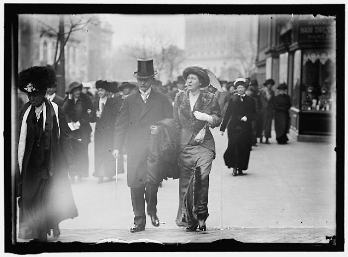 Vintage photograph showing elegantly dressed people walking on a city street, rare photographs rescued from glass negatives.