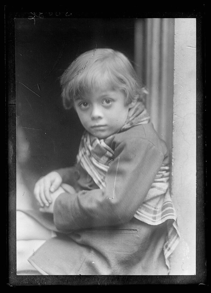 Black and white rare photograph of a young child with a scarf, restored from glass negatives for historical preservation.