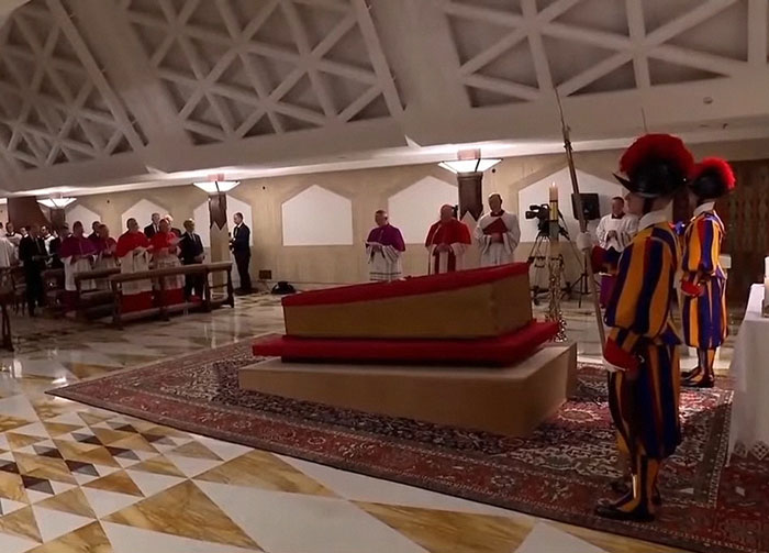 Pope Francis' open casket surrounded by clergy and guards in the Vatican.