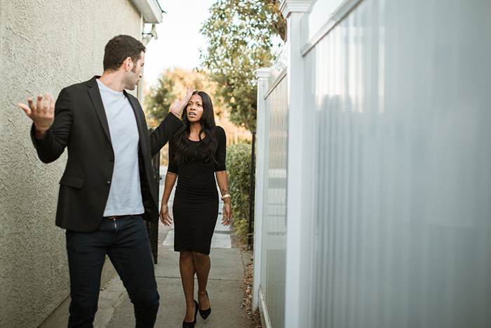 Man and woman arguing outdoors; possibly about a wedding's plus one policy.