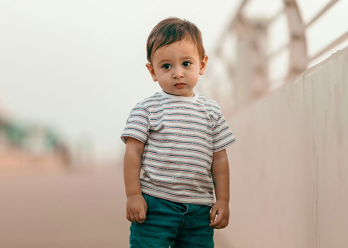 Young child in striped shirt standing outdoors, related to child services decision.