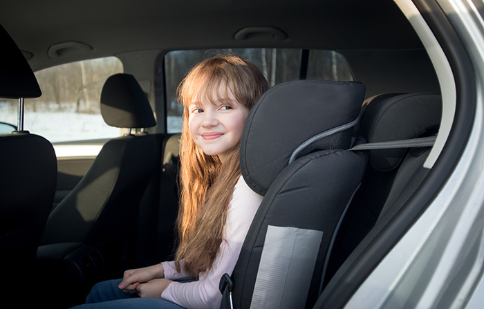 A smiling girl sits in a car seat, suggesting playdate excitement.