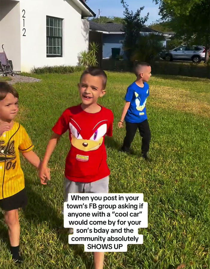 Children playing outside as community surprises a boy with sports cars for his birthday.