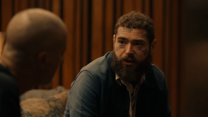 Two people in a candid conversation, one with visible tattoos, discussing pleasant celebrity encounters.