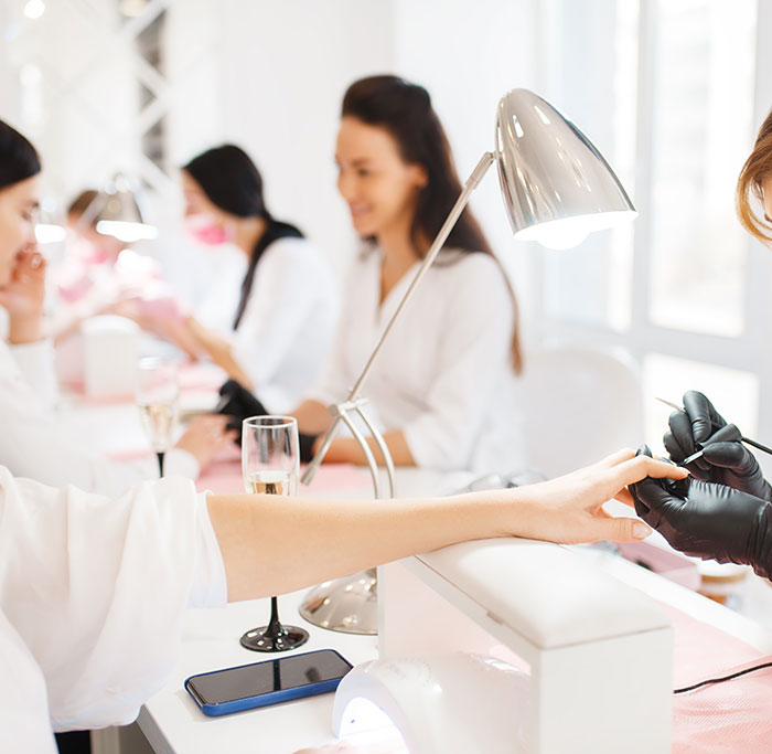 Women getting manicures in a bright salon, sparking discussion on patriarchy and nail trends. Women getting manicures in a bright salon, sparking discussion on patriarchy and nail trends.