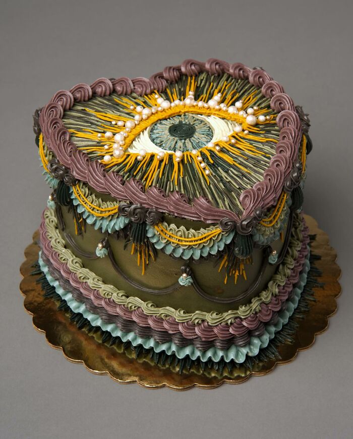 A visually stunning cake decorated with intricate vegan designs, featuring colorful swirls and an eye motif on top.