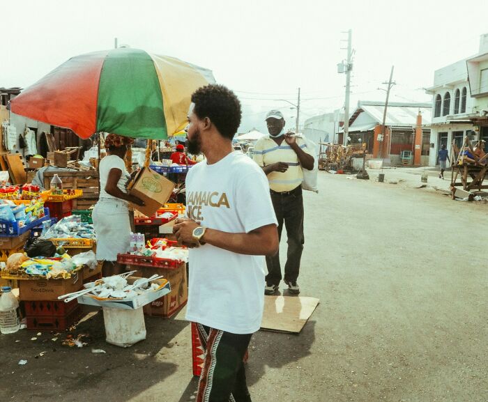 Market scene on the island with a man near a colorful umbrella and street vendors, showcasing local life.