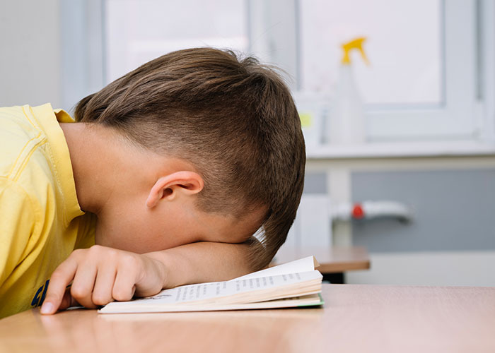 Child with head down on a book, appearing frustrated or overwhelmed, possibly due to a bad teaching experience.