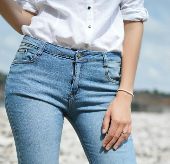 Person in denim jeans and a white shirt, standing outdoors, displaying casual fashion from the past.