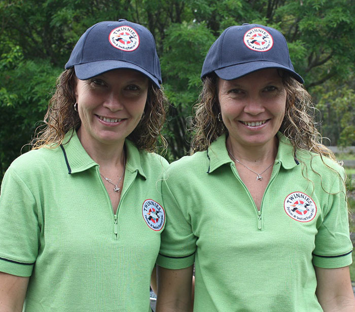 Twins wearing matching green shirts and caps, smiling outdoors, showing unity. Twins wearing matching green shirts and caps, smiling outdoors, showing unity.