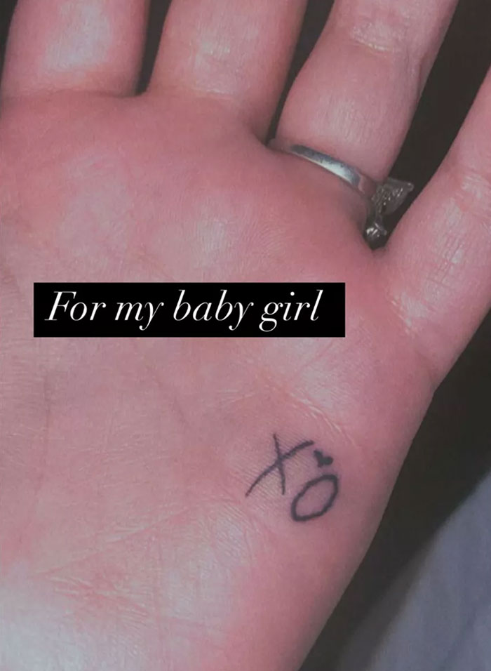 Hand with tattoo "xo" and ring, with text "For my baby girl" overlayed, linked to Demi Lovato.