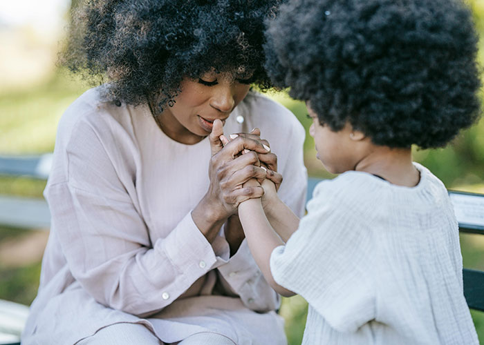 Woman and child holding hands outdoors, showing comfort and support related to heartbroken people and cheating experiences.