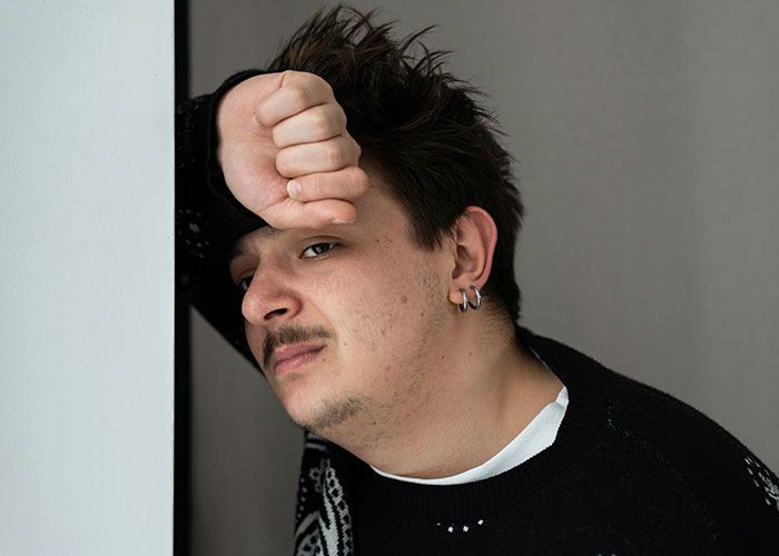 A person leaning against a wall, looking contemplative, related to HOA experiences.