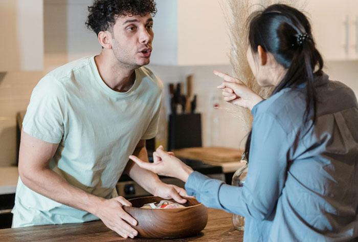 A young couple in a kitchen discussing over a bowl, illustrating a close family relationship dynamic.