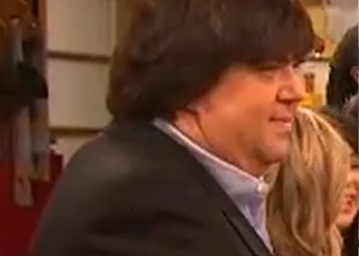 Man in a suit smiling during a public event, representing a wild rumor proven true.