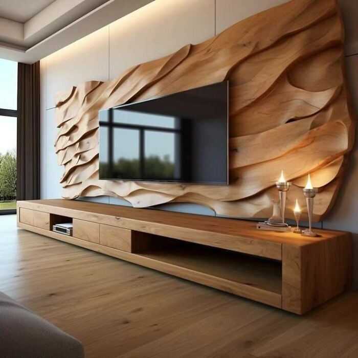 Mueble de madera moderno con diseño tallado y TV montada en sala iluminada con ventanas grandes y piso de madera.