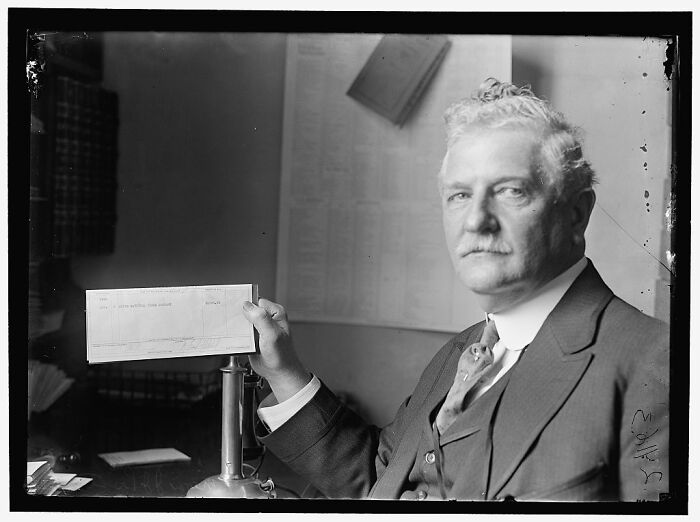 Vintage black and white photograph of a man in suit holding a document, rare photograph rescued from glass negatives.