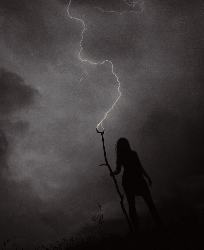 Silhouette holding a branch under lightning, showcasing dreamy dark escapism photography by Nona Limmen.