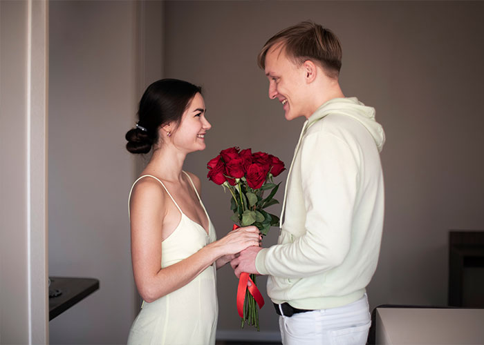 A man giving a bouquet of red roses to a smiling woman, illustrating a marriage cheat code that works.