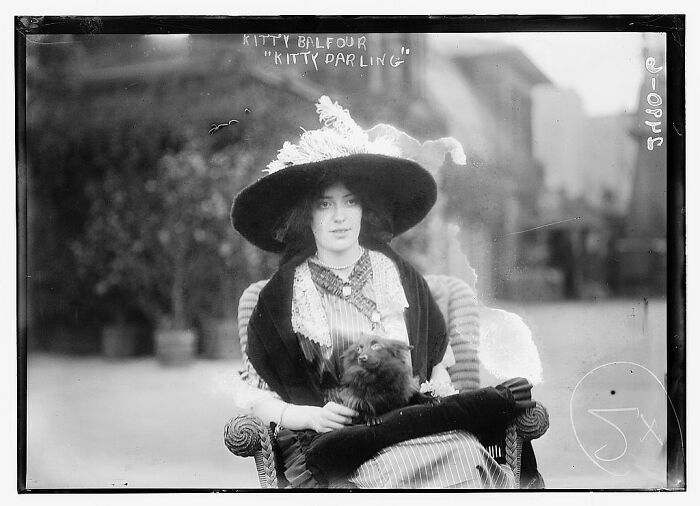 Early 20th century woman in vintage attire seated with a small dog, from rare photographs rescued from glass negatives.