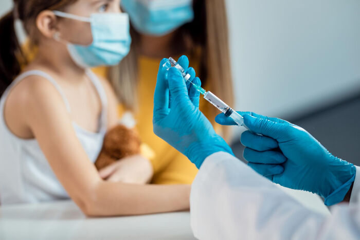 Healthcare worker prepares a vaccine for a masked child, illustrating under-radar scientific advancements.