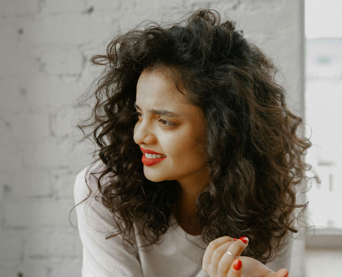 Woman with curly hair and red lipstick, following break policy, watching kitchen chaos unfold.