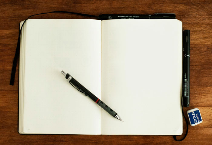 Open notebook with pen on wood table, symbolizing job hunting strategies.