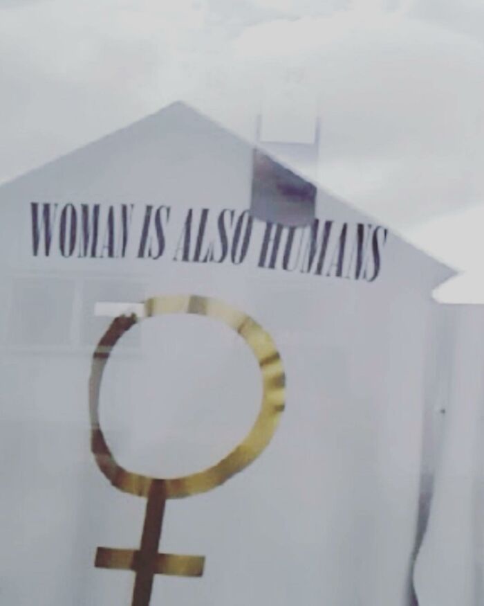 T-shirt with text, "Woman is also humans," highlighting translation humor with a female symbol design.